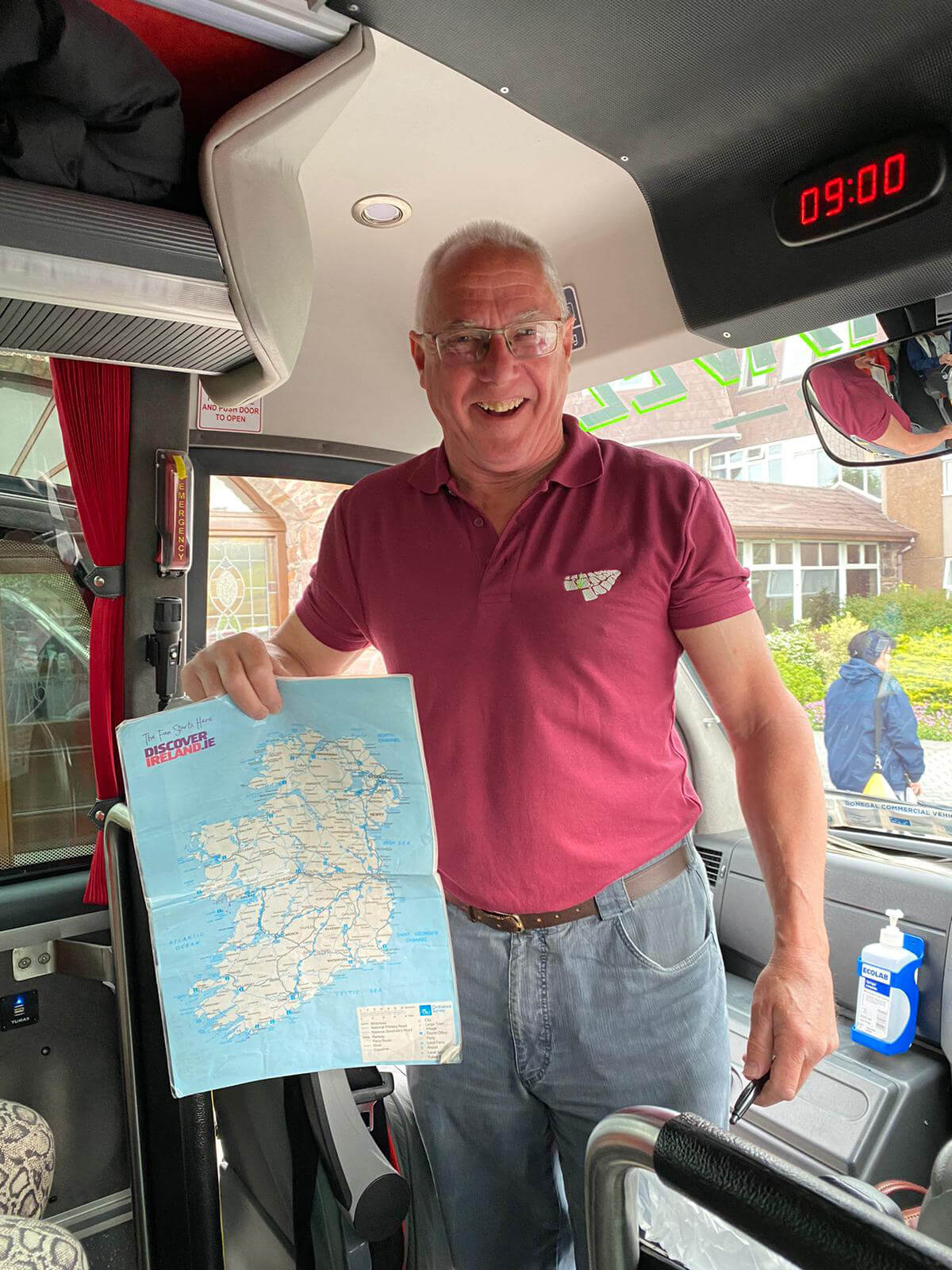 Mature man wearing burgundy polo t-shirt, holding a map of Ireland