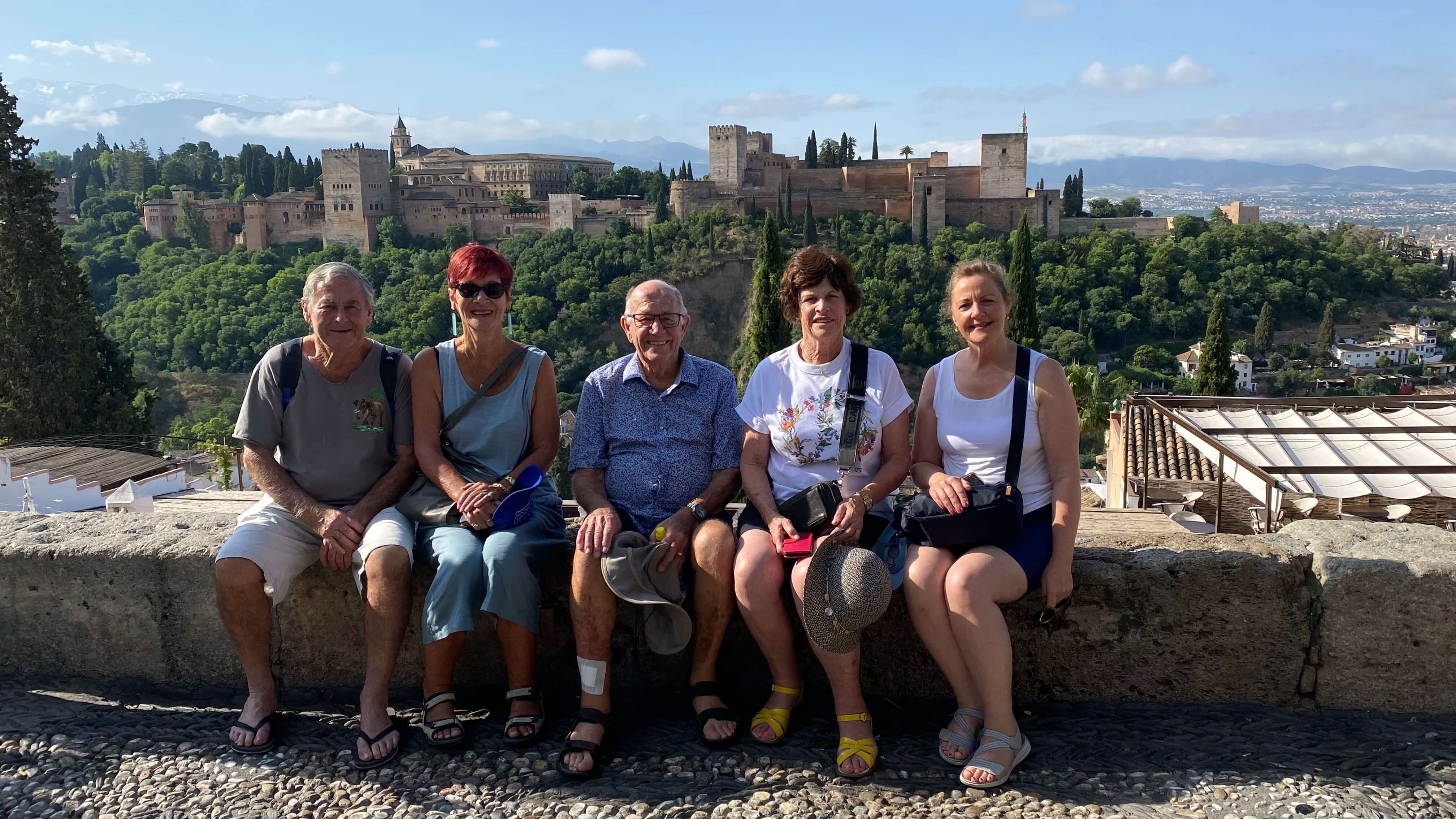 Group of people sat on wall with beautiful backdrop of Portugal