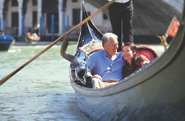 middle aged couple in an embrace smiling and enjoying a gondola ride in Venice