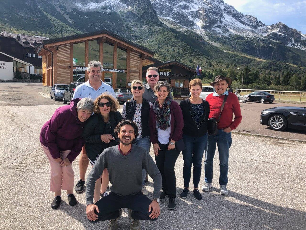 Group of clients with Tour Leader standing in front of large snowcapped hills.