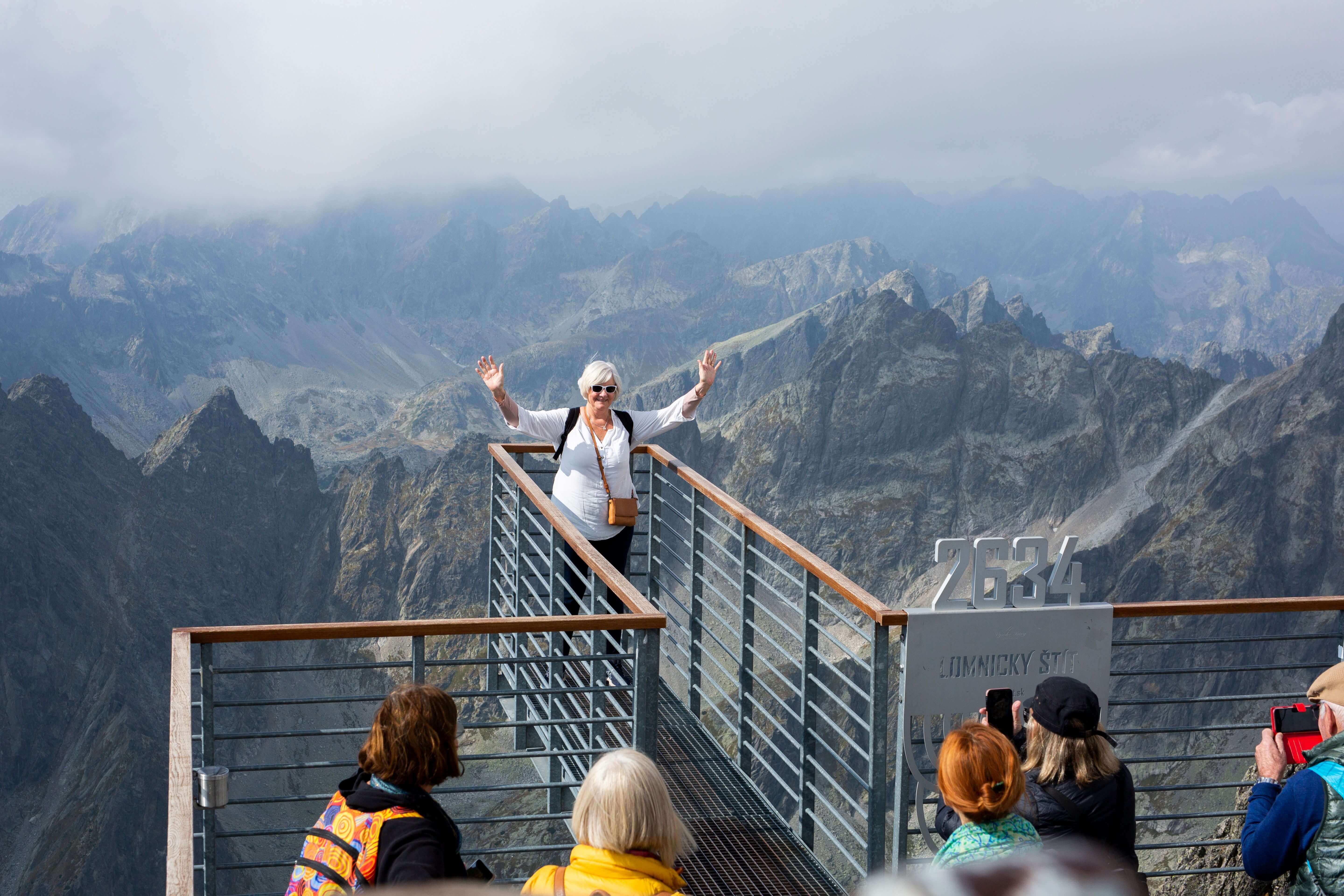 Mature woman posing for photo with hands in their air at Lomnicky Peak at High Tatras Mountains