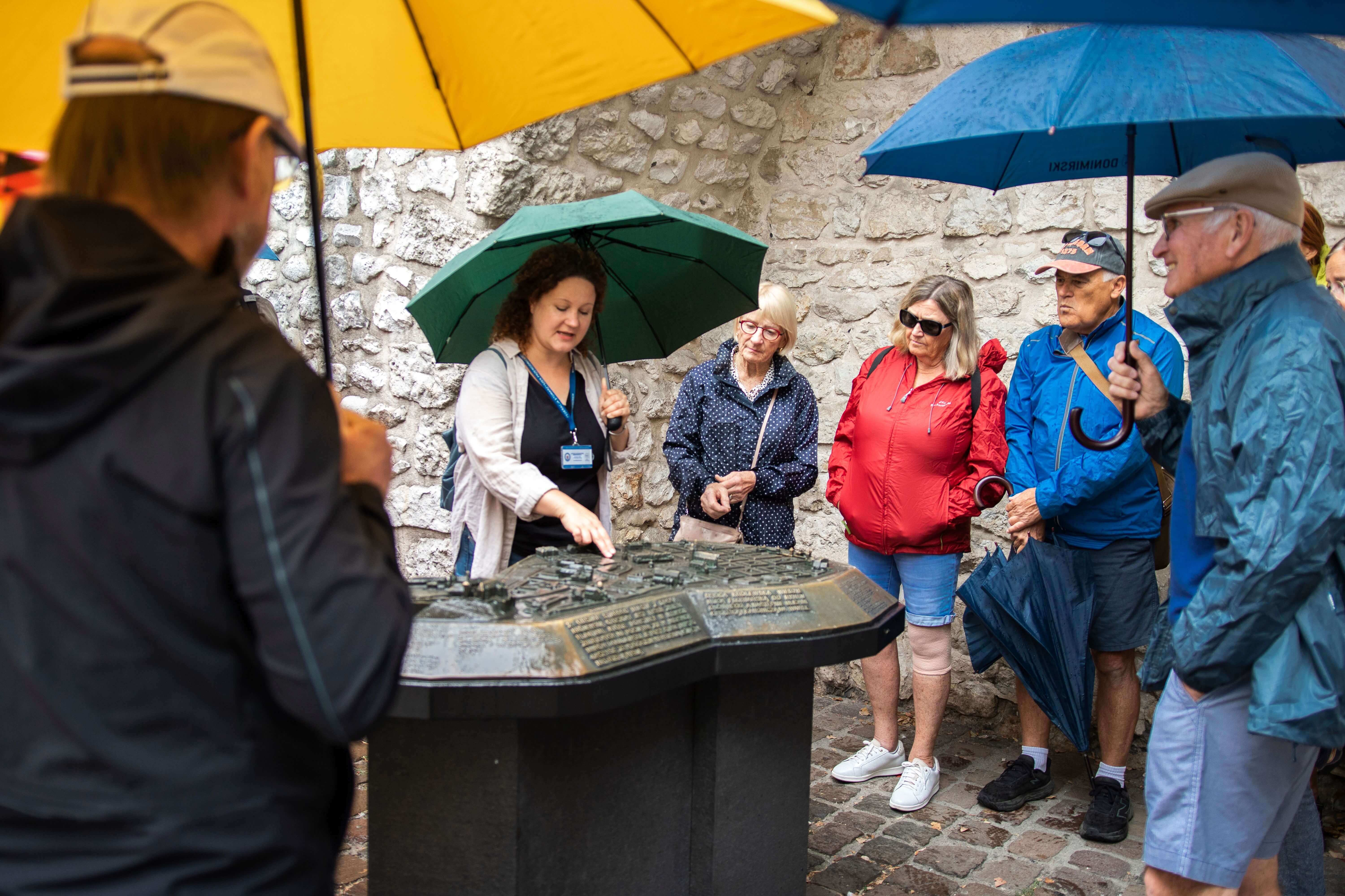 Local female guide showing group a marble miniature of Kraków