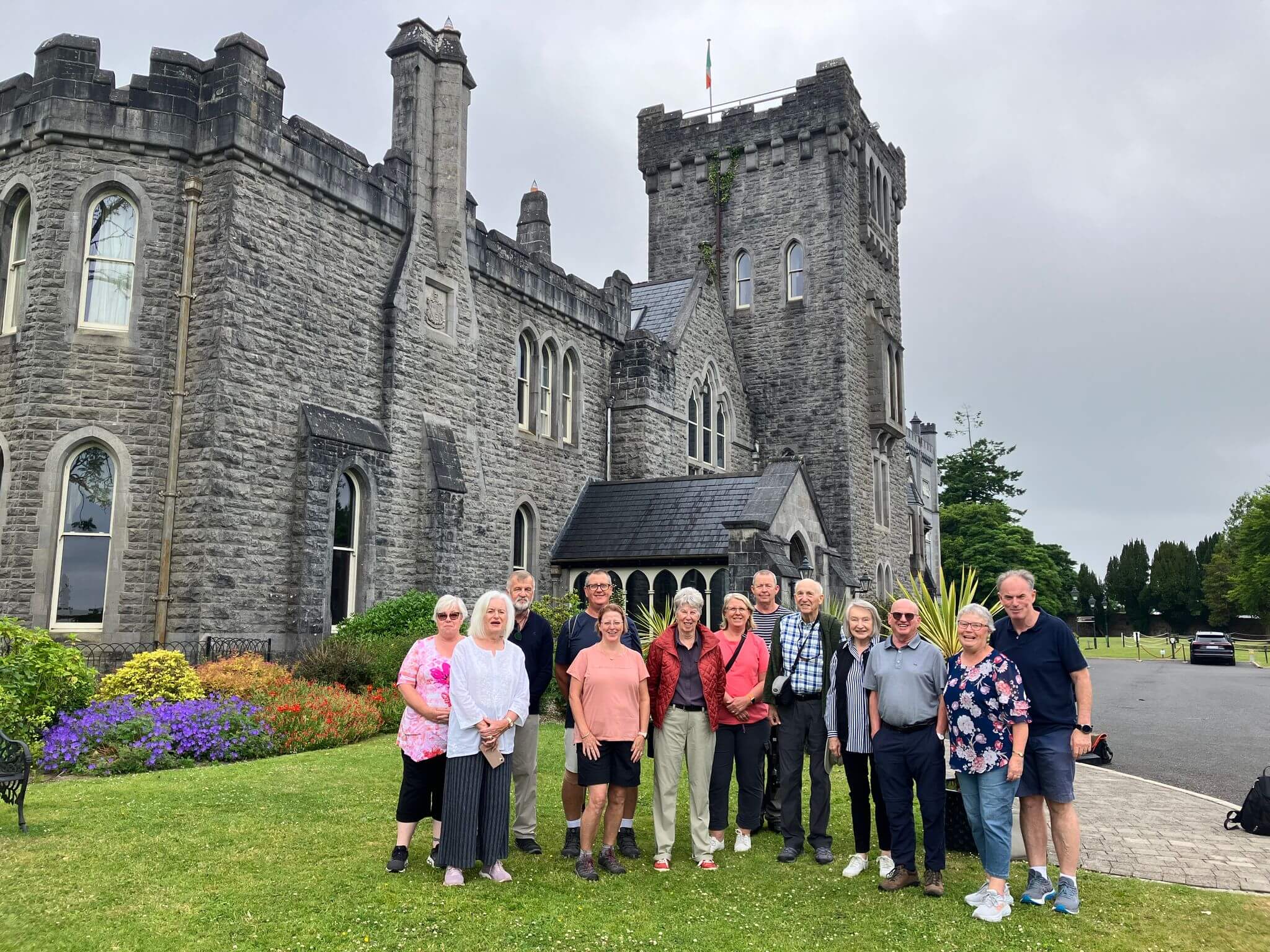 Group of mature adults smiling together in front of an Irish castle