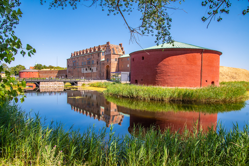 view of the moated Malmöhus Castle, Sweden, framed by trees and on a sunny day