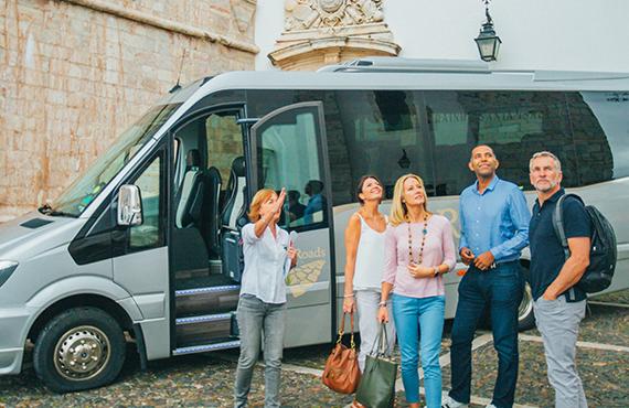 Tour group posing for a photo outside a tour bus.