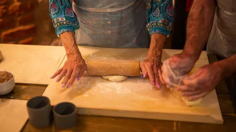 Travellers flattening dough with a rolling pin as part of a Croatian cooking class.