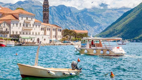 Boats cruise around the historic Bay of Kotor on a sunny day.