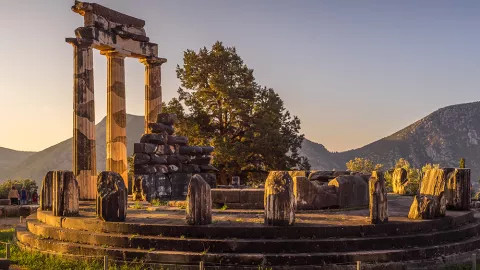 A view of the Tholos of Delphi at dusk, among the collection of ruins that made up the sanctuary of Athena.