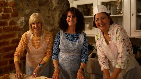 Three travellers smiling towards the camera during a cooking class.