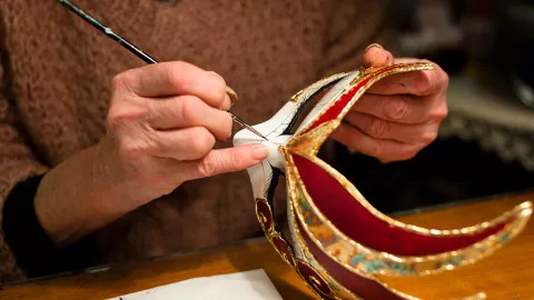 A treveller painting an exotic mask at a Venetian Mask making workshop.