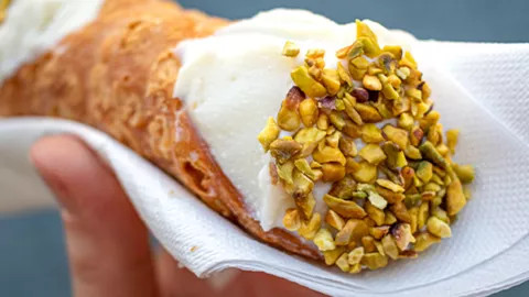 A cannoli filled with cream and pistacchio.