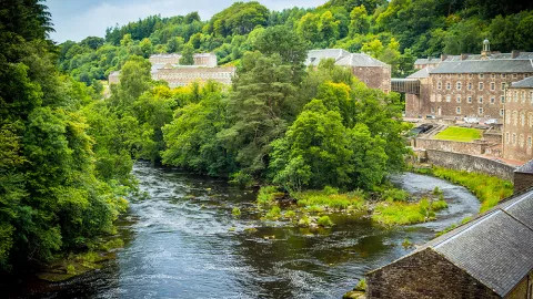 A river courses through the small village of New Lanark, a UNESCO heritage site.