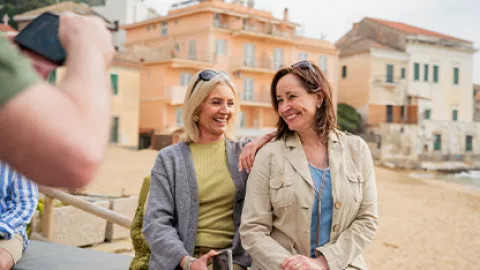Women pose for photo by a beach in Italy