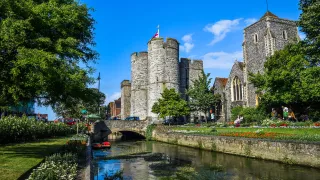 A view of a feudal castle by a canal in the city of Canterbury.