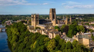 An aerial view of the impressive Durham Cathedral and the surrounding town at dusk.