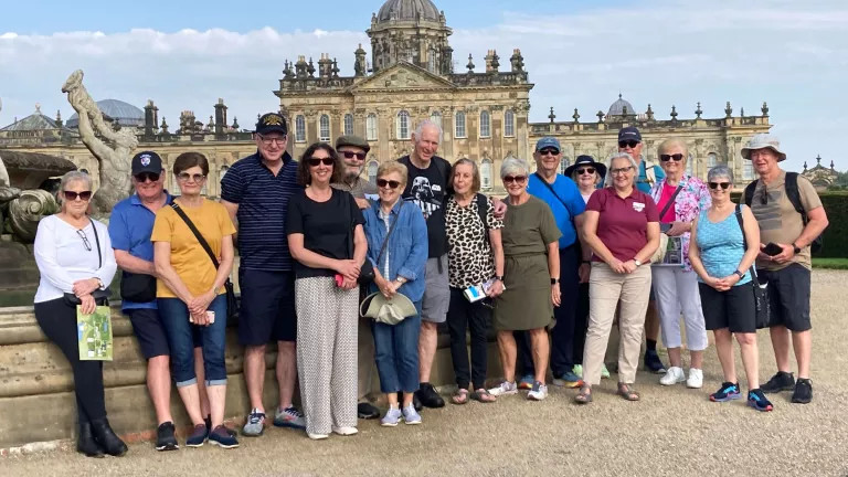 Group of mature adults standing together in front of British monument