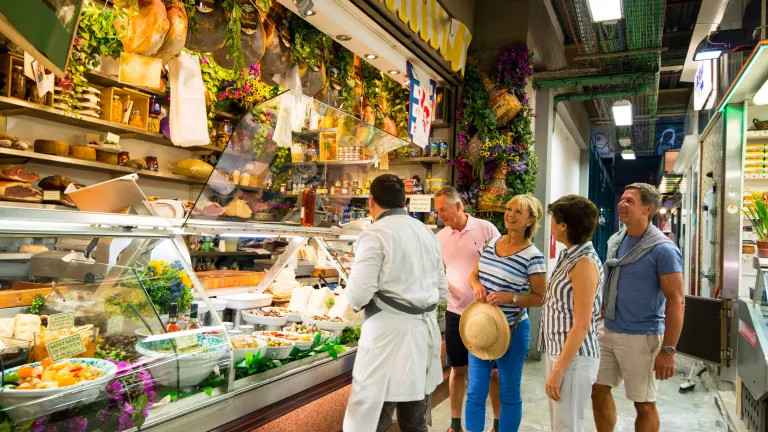 group of mature travellers conversing at a European market stall