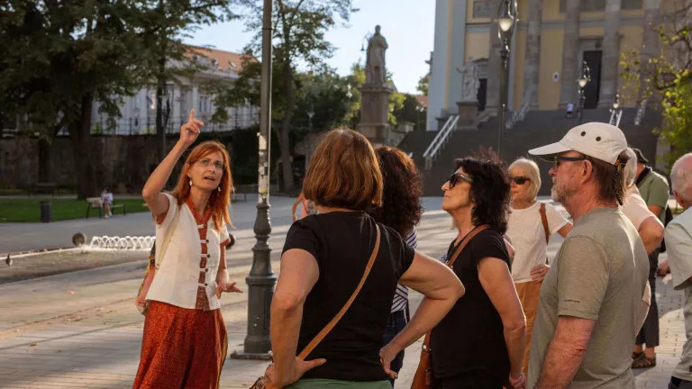 Female Tour Leader pointing out a building to a small group during orientation walk