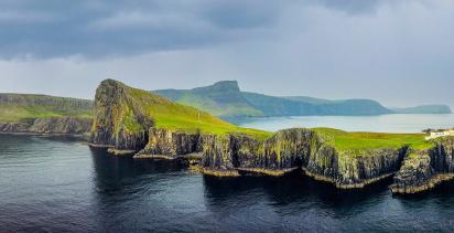 The Isle of Skye with the famous Neist Point lighthouse visible under a stormy sky.