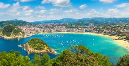 An aerial view of the portside city of San Sebastian on a sunny day, blue waters lining the coastline.