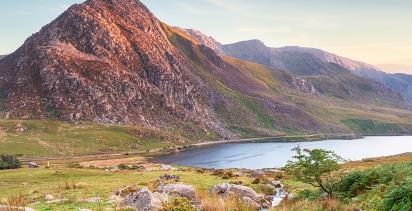 A landscape view of the famous Snowdonia national park in Wales, it's natural fauna and cliff faces shining in the evening glow.