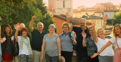 A group of travellers pose for a photo in front of an old french town.