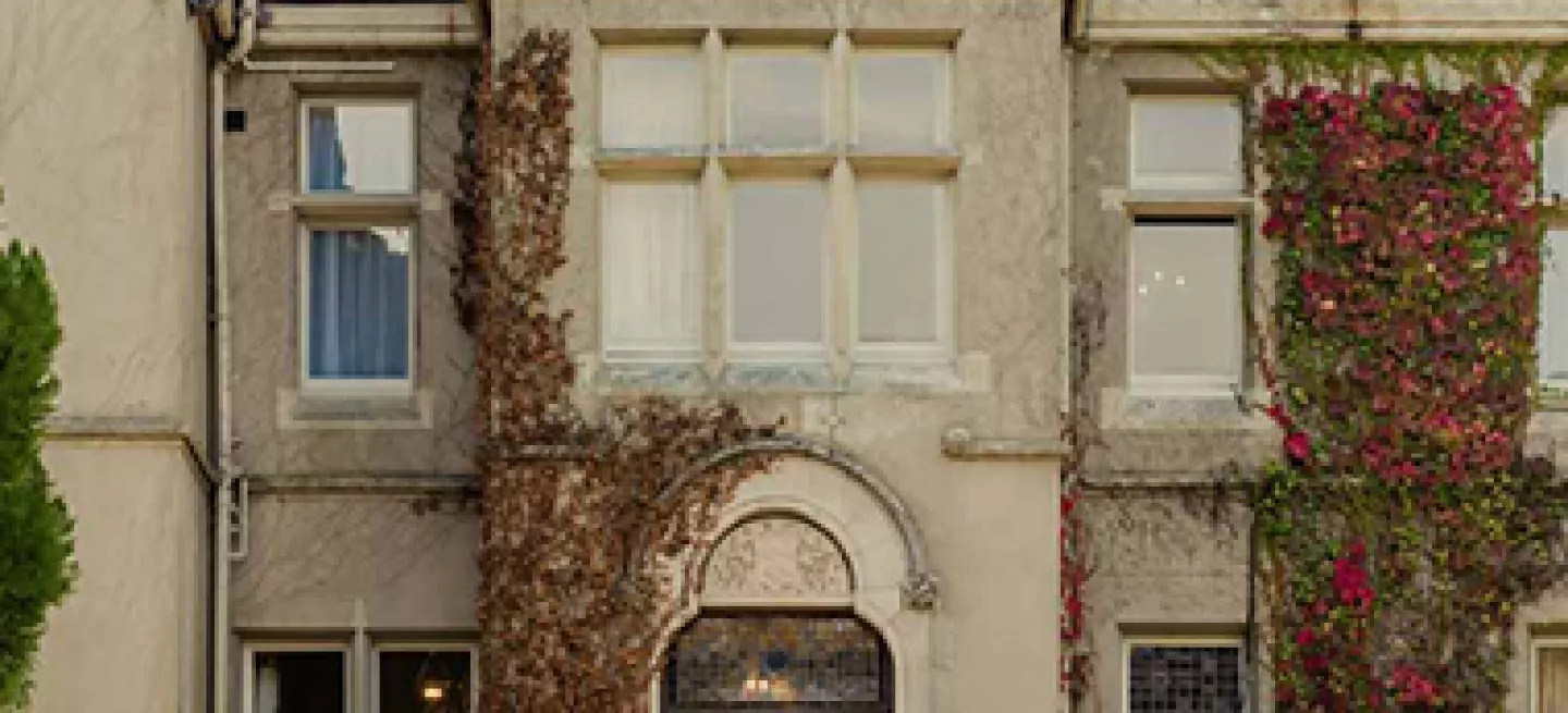 Historic ivy-covered hotel, with a vintage car parked in front.