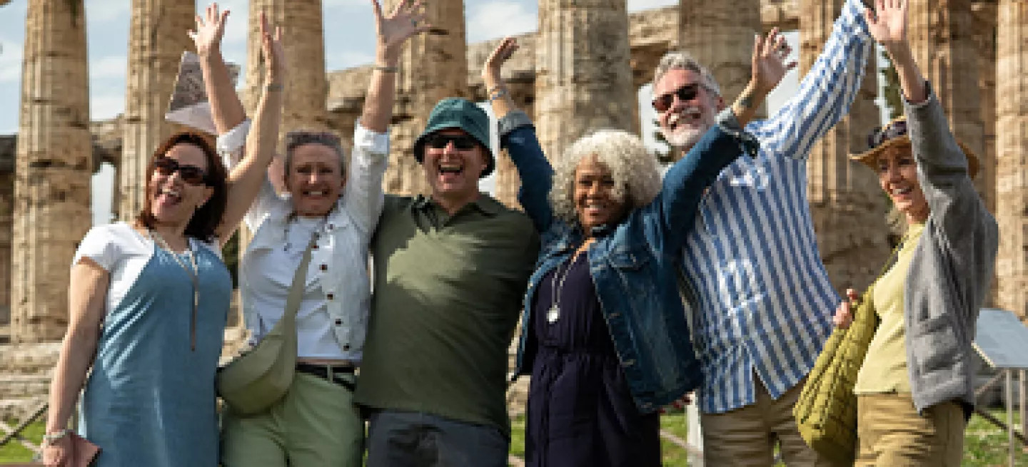 A tour group posing in front of the Temple of Hera at the Paestum archaeological site, Italy.