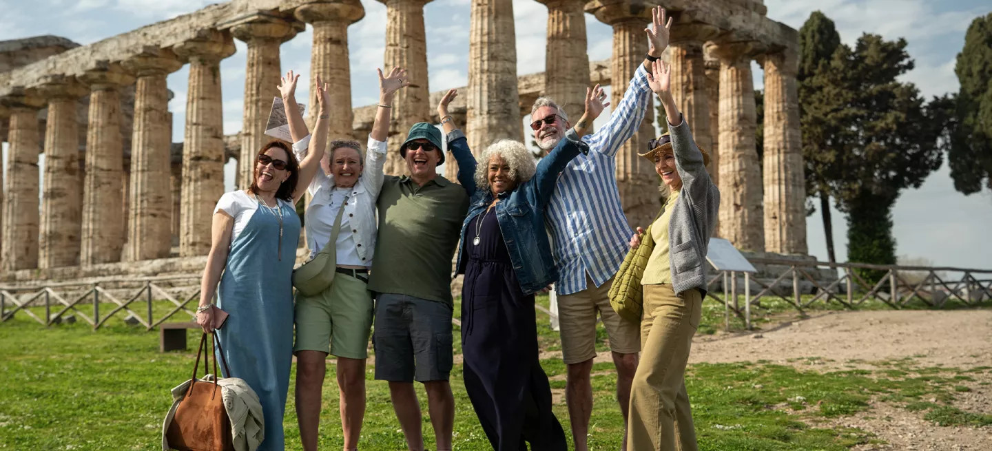 A tour group posing in front of the Temple of Hera, an archaeological site in Italy.