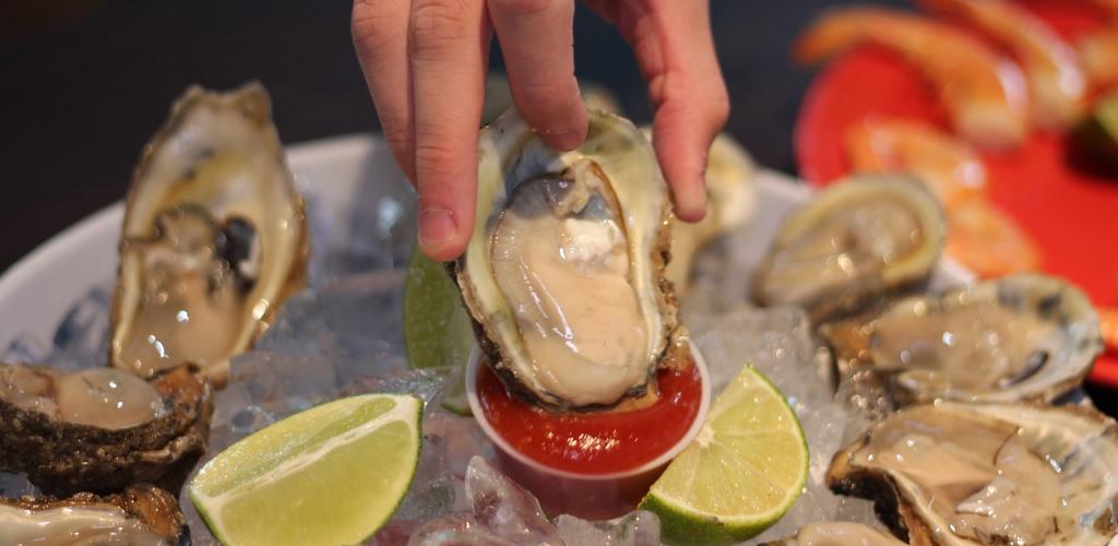 person dipping oysters in sauce