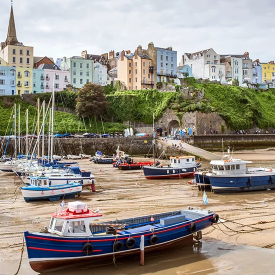 Boats rest on the harbor at low tide at the idyllic Welsh town of Tenby.